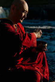 Monje budista tocando cuenco tibetano en el mar